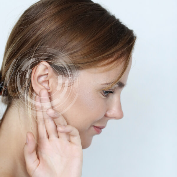Une femme avec l'oreille posée sur le côté, semblant écouter attentivement quelque chose.